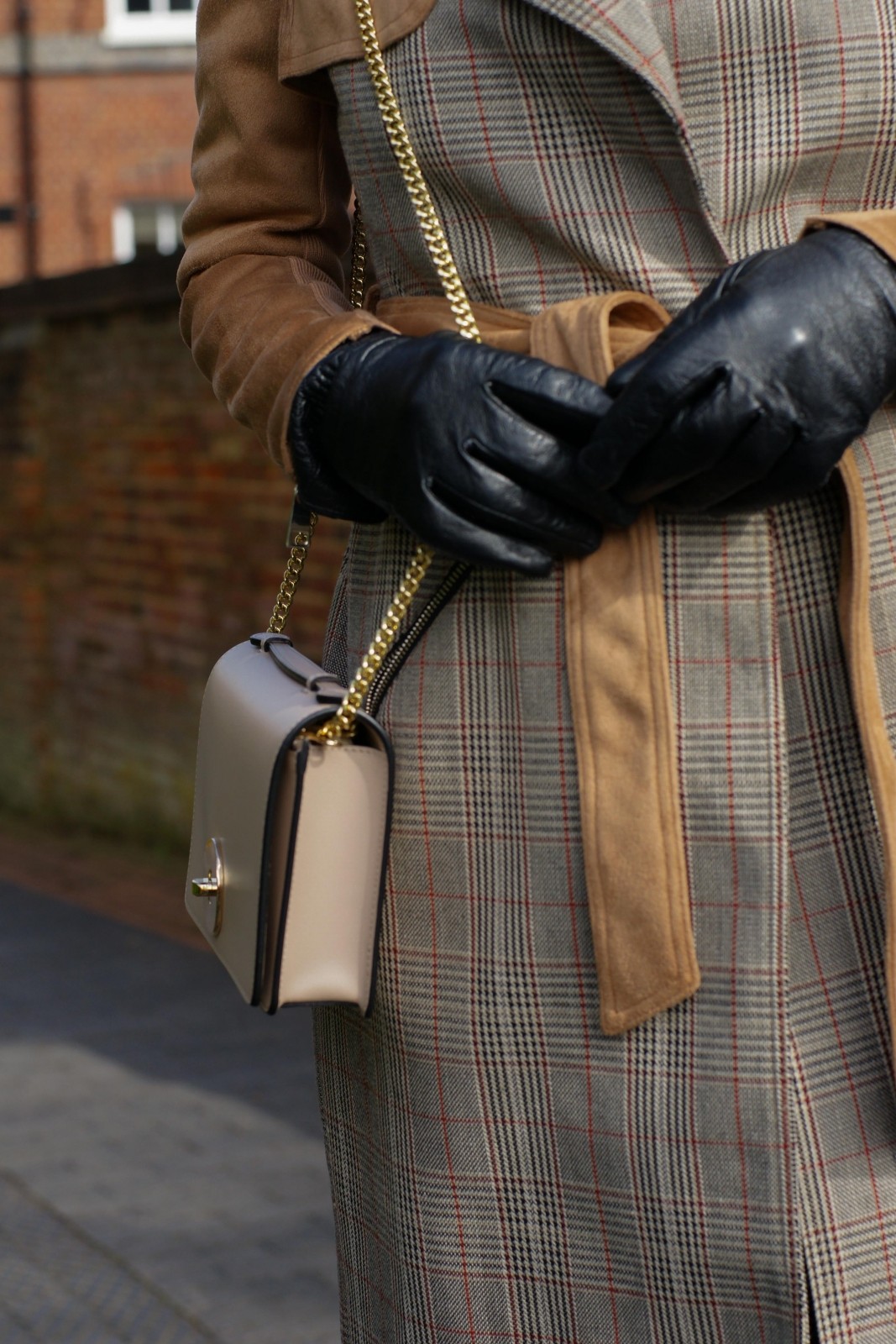 Light brown check trench coat with black leather gloves