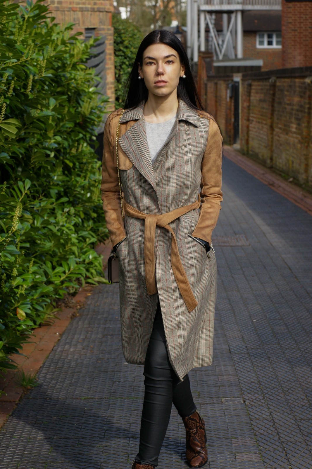 Brunette blogger wearing checked trench while walking