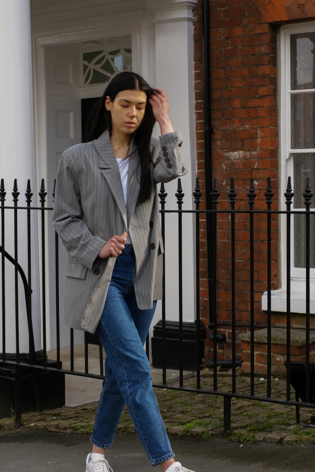Brunette girl walking in jeans and white trainers with suit blazer
