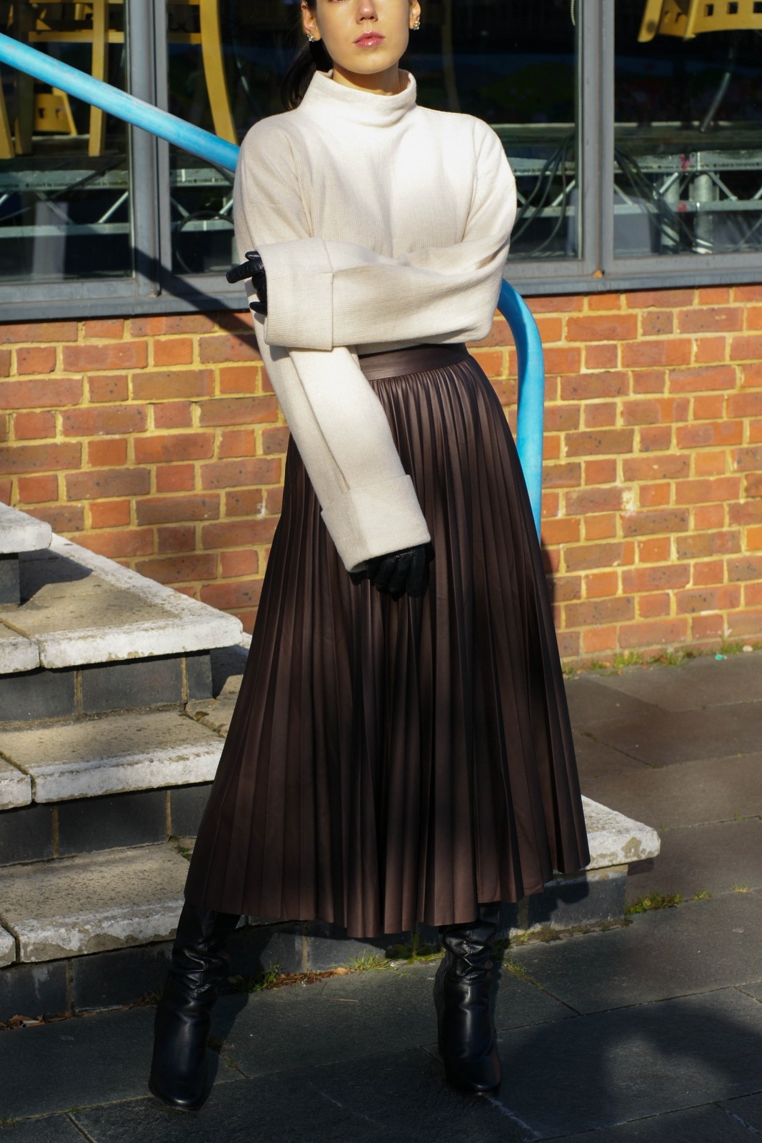 girl wearing a white jumper and brown leather pleated skirt